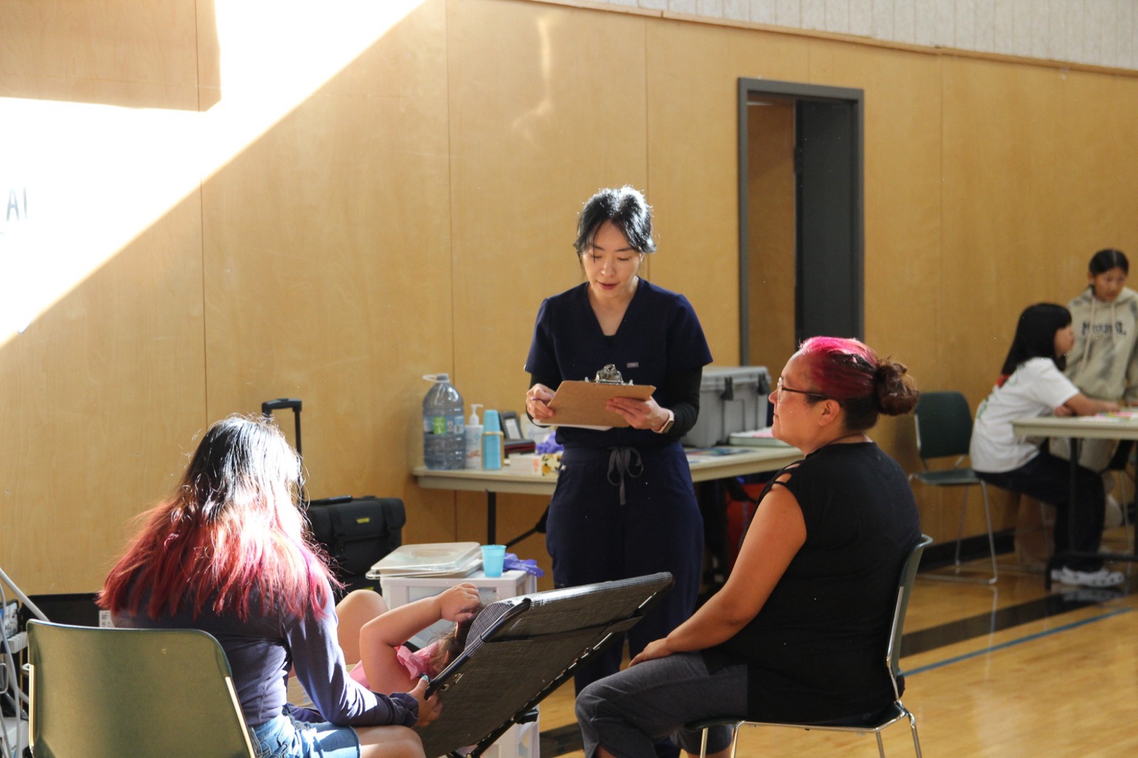 A hygienist with a clipboard talks with a mother during intake