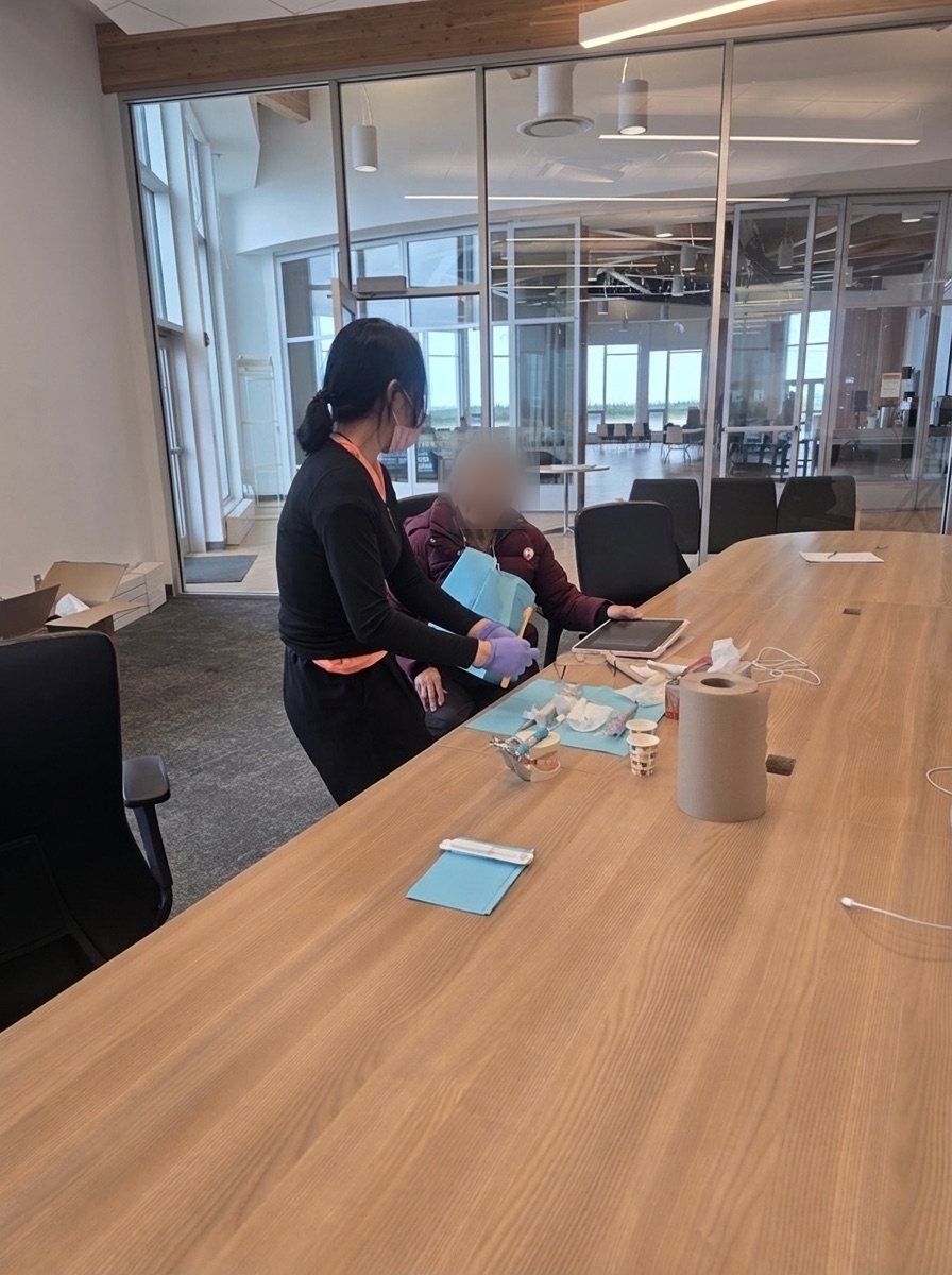 One-on-one oral hygiene instruction with an elder at a table with brushing supplies