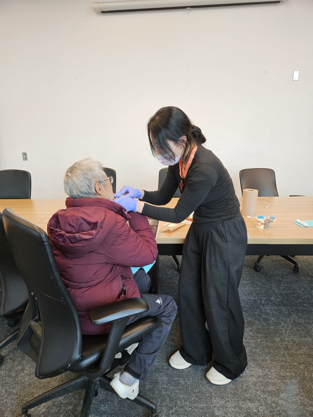 A hygienist leans in to examine a community elder at the Old Crow health centre